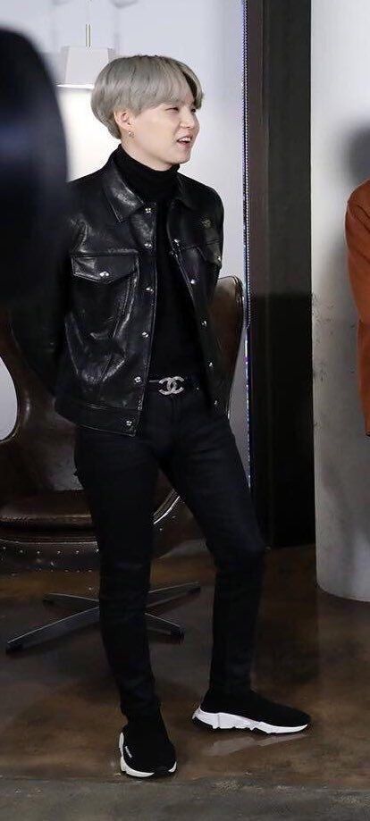 the boy is wearing a black leather jacket and standing in front of a mirror with his hands on his hips