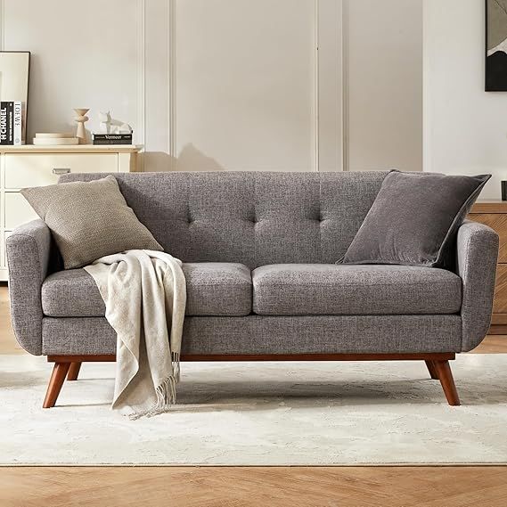 a living room with a gray couch and white rug