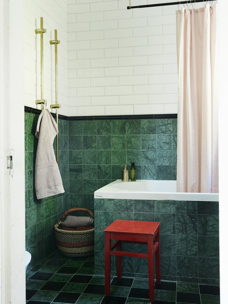 a green tiled bathroom with a red stool