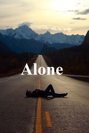 a person laying down on the side of an empty road with mountains in the background