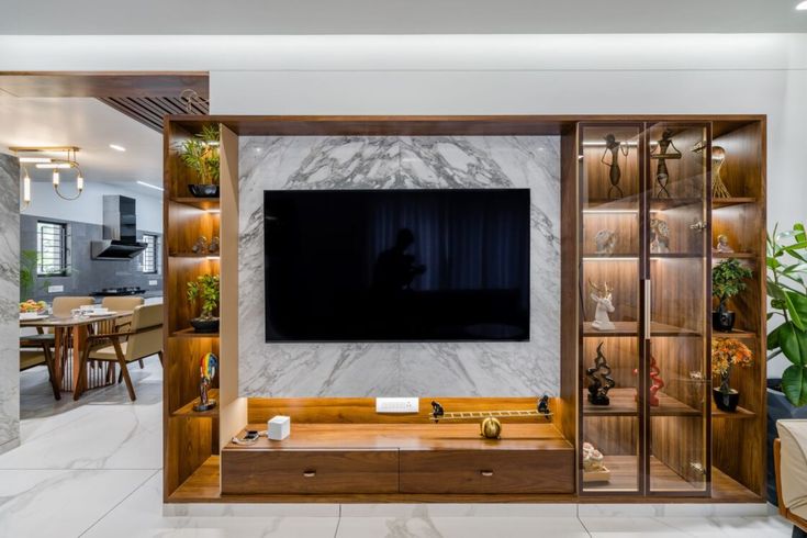 a living room with a large television mounted on the wall and wooden shelves in front of it