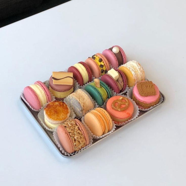 a tray filled with assorted macaroons on top of a white countertop