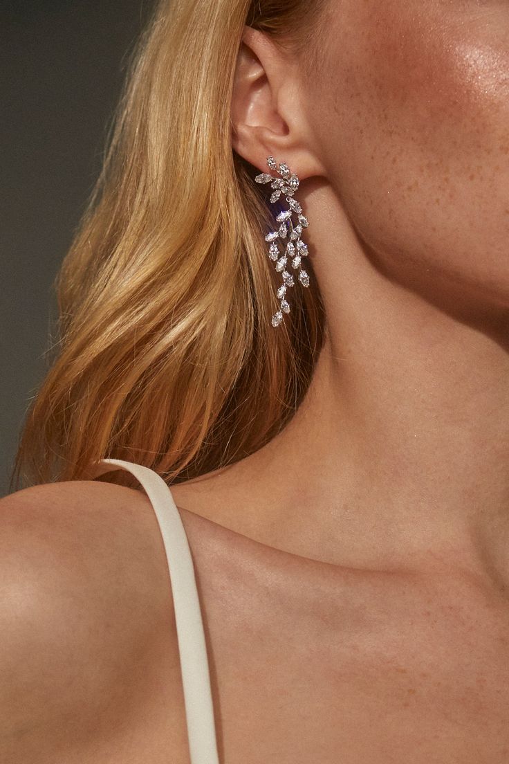 a woman with blonde hair wearing earrings on her ear and looking off to the side