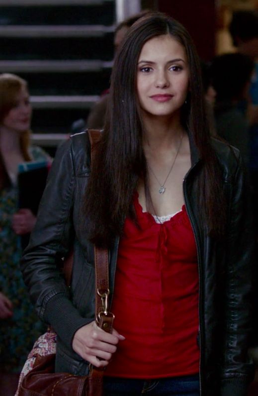 two women standing next to each other in front of stairs, one holding a purse and the other looking at the camera