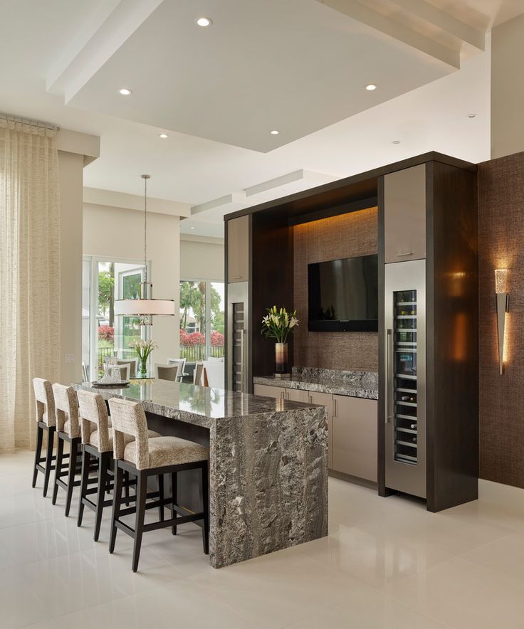 a modern kitchen with marble counter tops and stainless steel appliances, along with bar stools