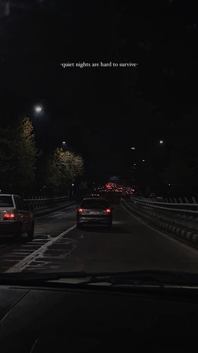 two cars are driving down the road at night