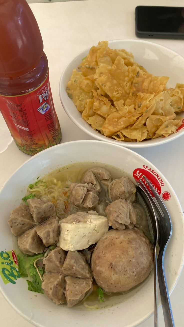 two bowls filled with food next to a bottle of soda