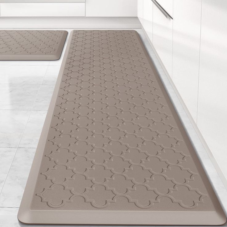 three bath mats in the middle of a bathroom with white walls and floor tiles on either side