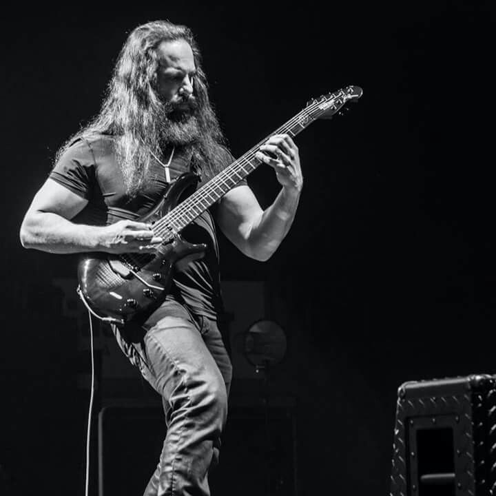 a man with long hair playing an electric guitar