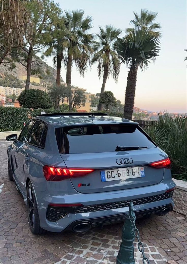 an audi car parked in front of some palm trees