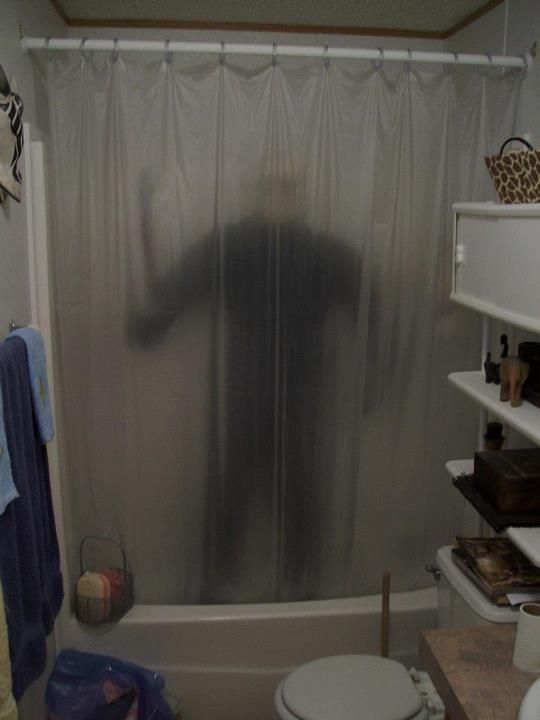 a bathroom with a shower curtain that has a person on it in the bathtub