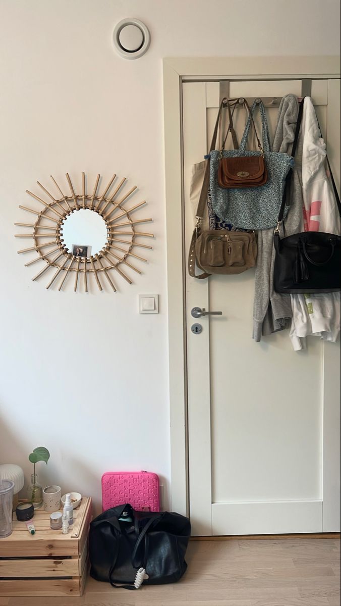 a white door with a mirror and purses hanging on the wall next to it