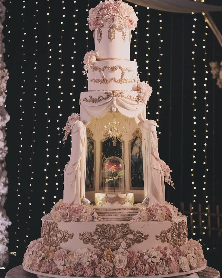 a wedding cake with flowers and candles on the top is surrounded by fairy lights,