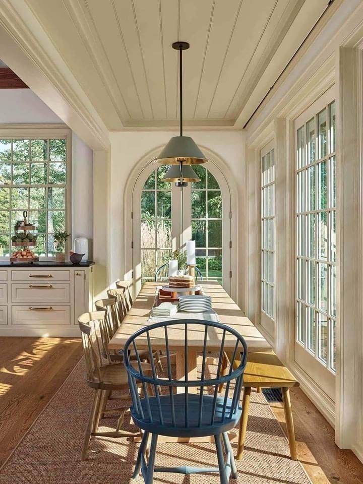 a dining room table and chairs in front of an arched window with lots of windows