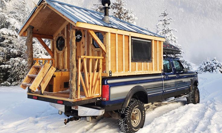 a truck is parked in the snow with a small cabin on it's back