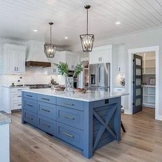 a large kitchen with white cabinets and blue island