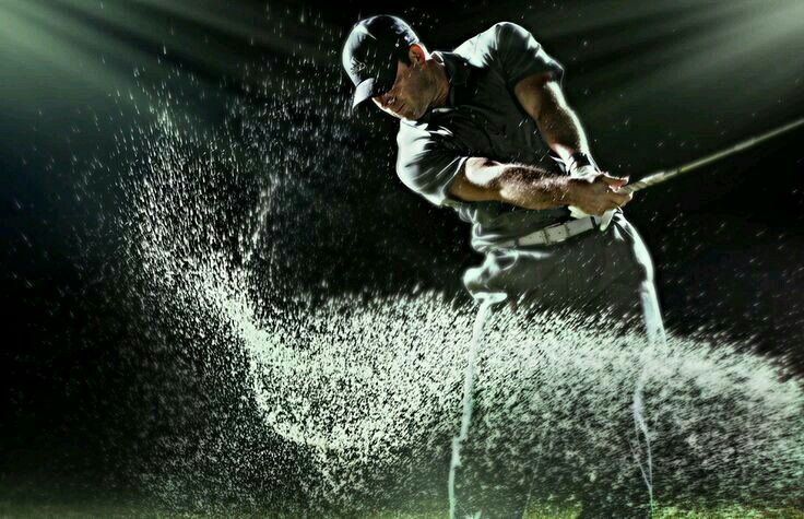 a man swinging a golf club in the rain