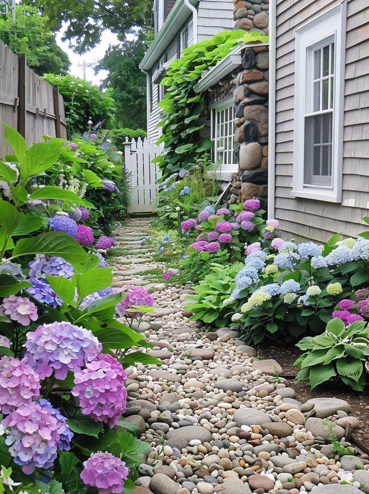 a garden with rocks and flowers next to a house