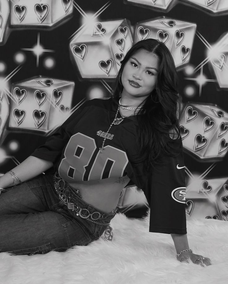 black and white photograph of a woman sitting in front of a wall with hearts on it