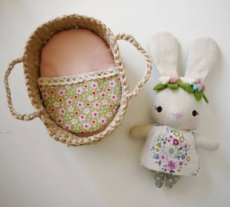 a stuffed bunny next to an egg in a basket on a table with white background