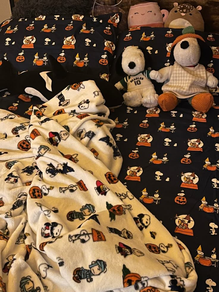 two stuffed animals sitting on top of a bed next to pillows and blankets with mickey mouses all over them