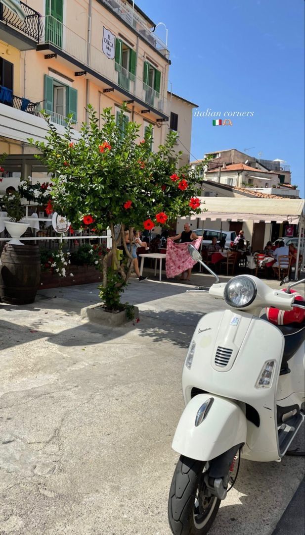 a white scooter parked on the side of a road next to a building