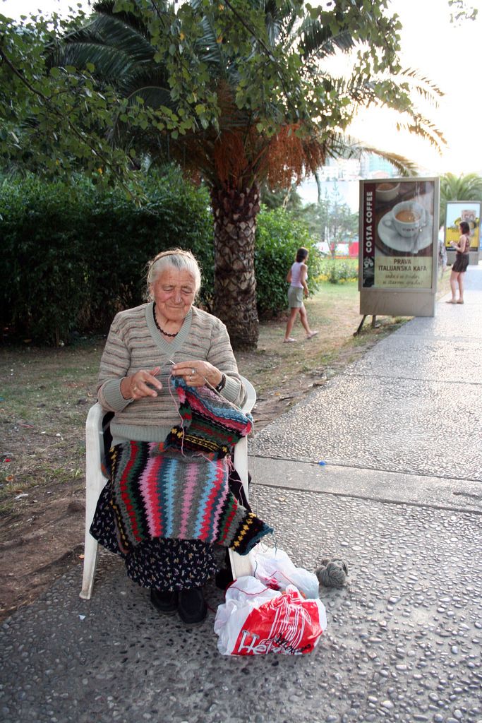 an older woman sitting on a chair next to a bag and some bags in front of her