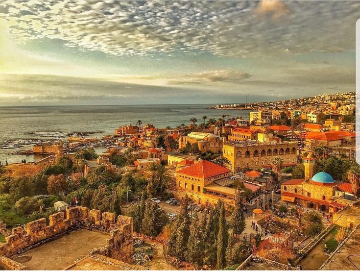 an aerial view of a city by the ocean with clouds in the sky above it