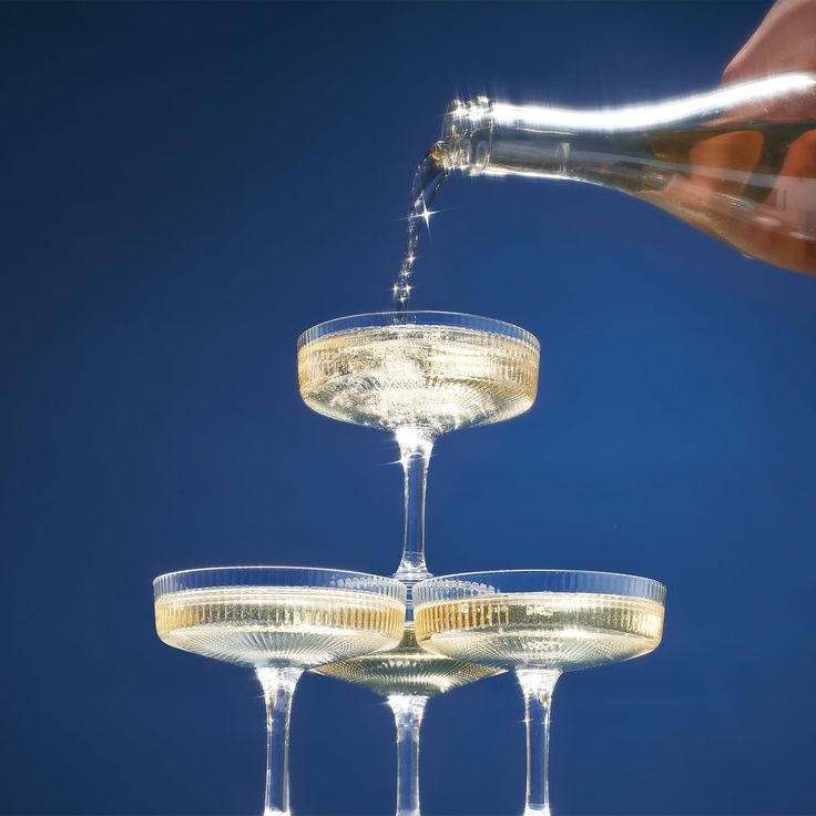 champagne being poured into three wine glasses