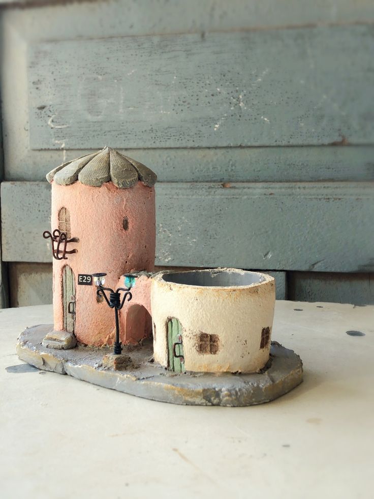 a clay model of a pink house on a white table next to a blue door