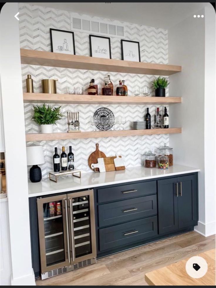 a kitchen with open shelving and wine bottles on the counter top, in front of a white chevron wall