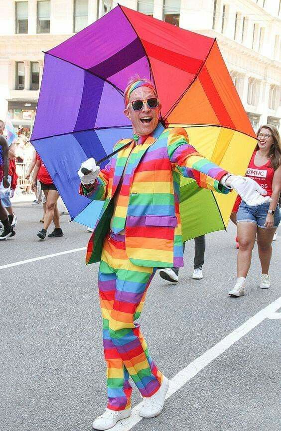 a man dressed as a clown holding an umbrella in the middle of a city street