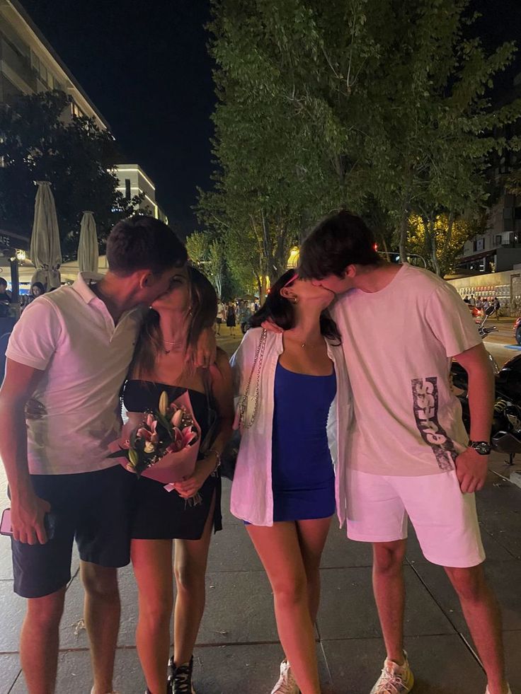 three people are standing on the sidewalk kissing each other while one person is holding his head in front of him