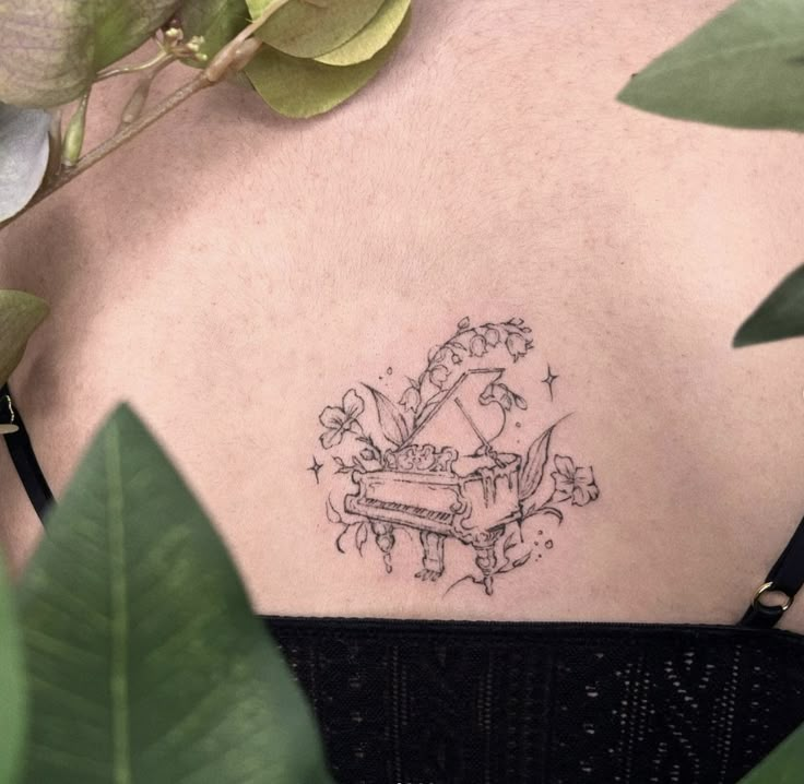 the back of a woman's shoulder with a tattoo design on her left side