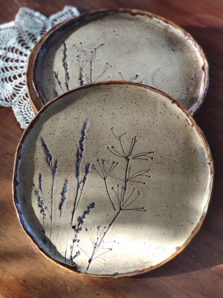 two plates sitting on top of a wooden table next to a white doily lace