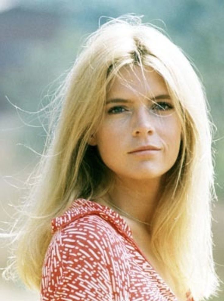 a woman with long blonde hair wearing a red and white shirt looking off to the side