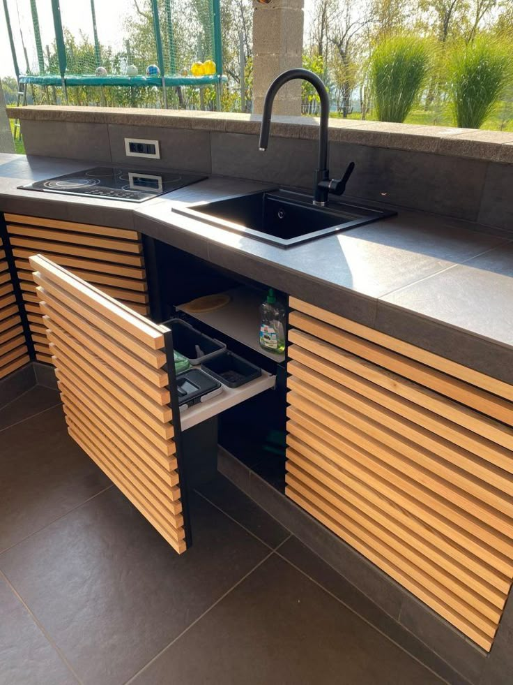 a kitchen with a sink and wooden slats on the counter top next to a window