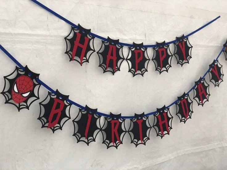 a spiderman birthday banner hanging on a wall with the word happy written in red and black