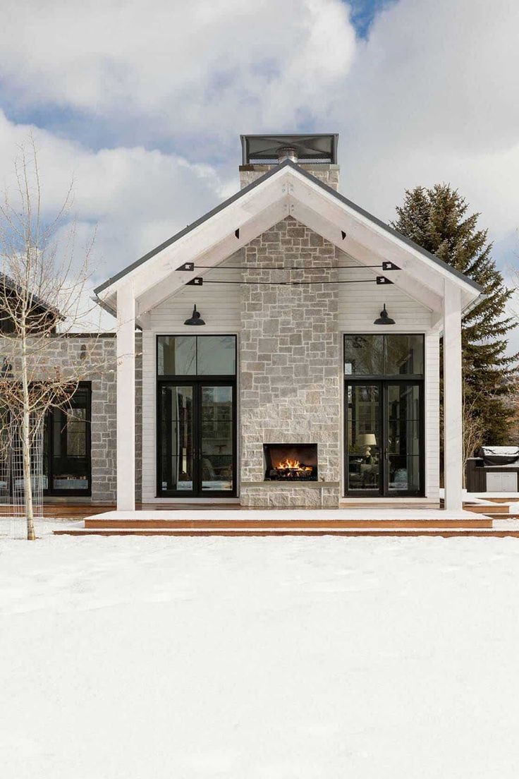 a white house with a fireplace in the middle of it and snow on the ground