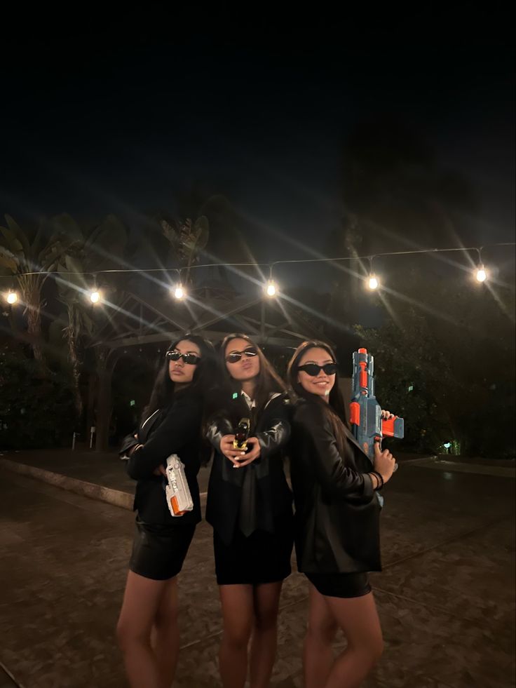 three young women are posing for the camera at night with their arms around each other