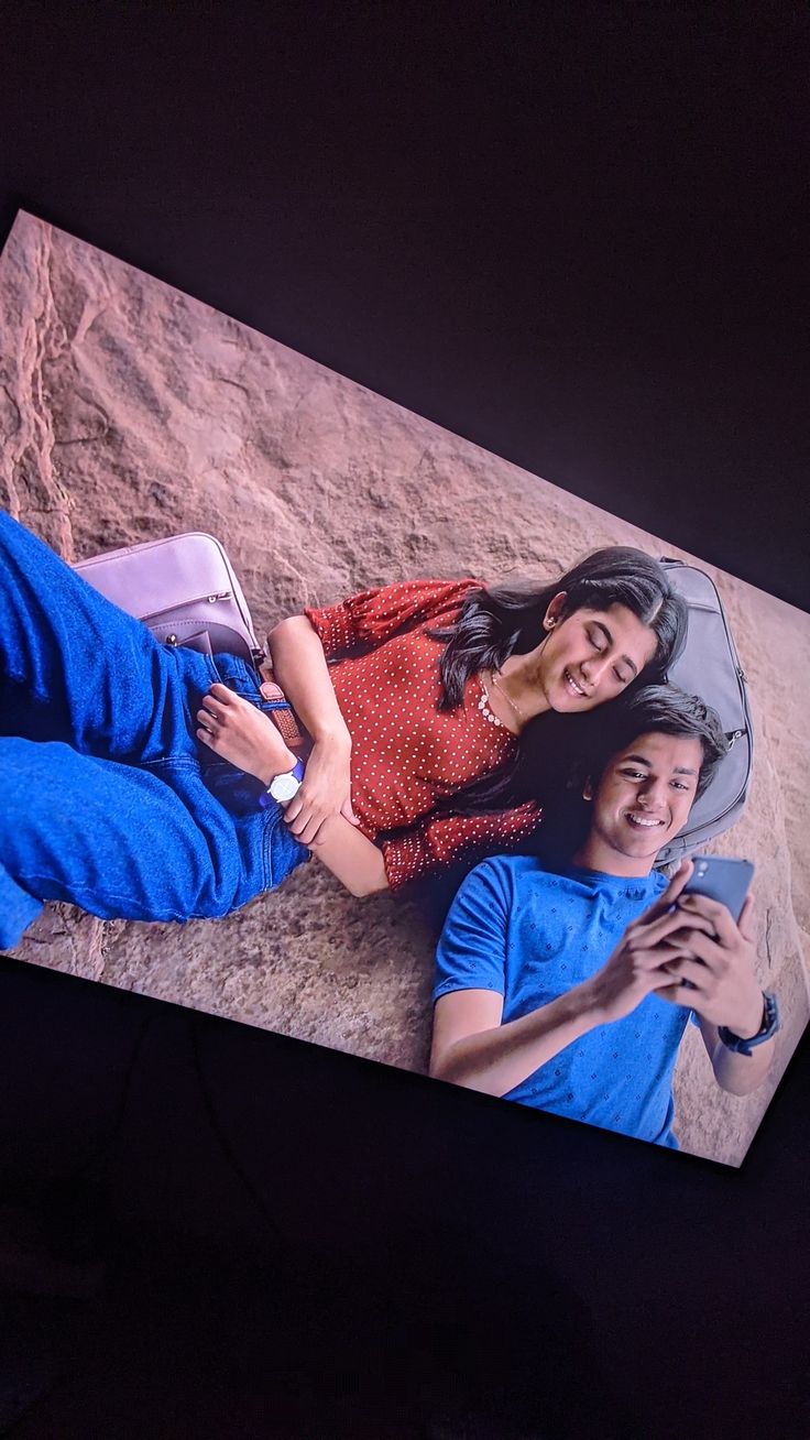 a man and woman laying on the ground in front of a large screen with an image of them