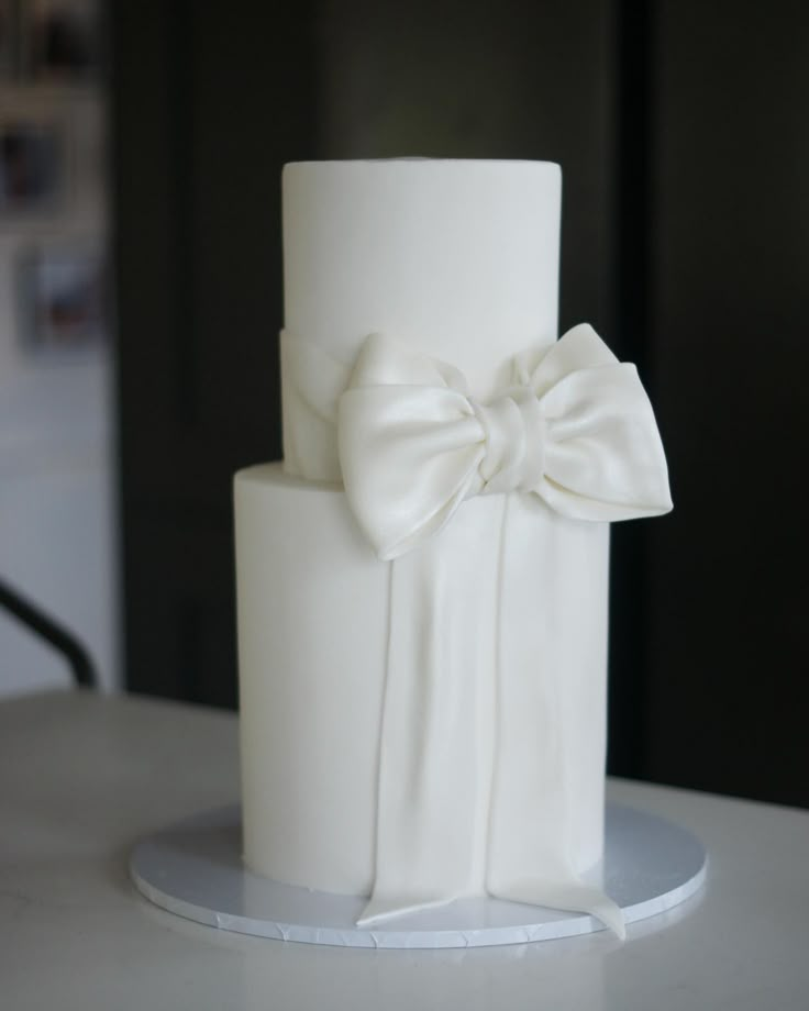 a close up of a white cake with a large bow on the front and side