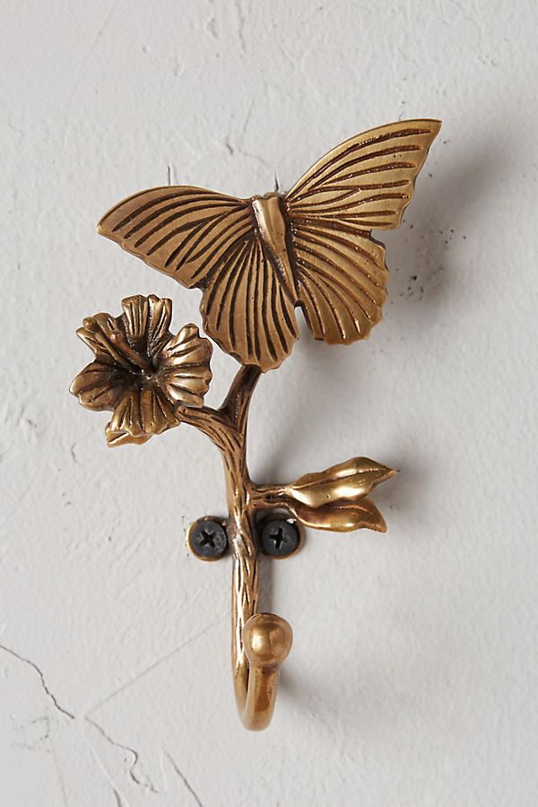 a gold brooch with a butterfly on it's back and flowers in the middle