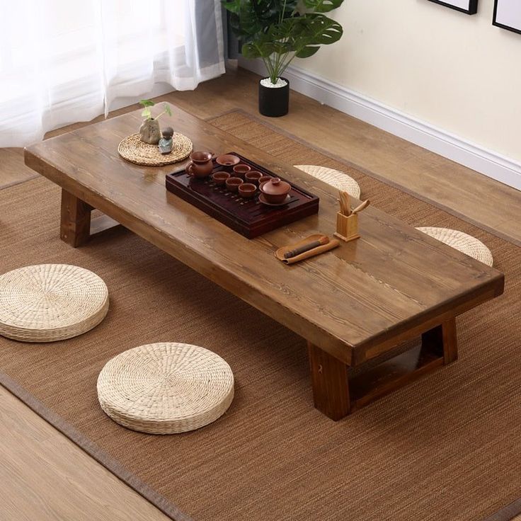 a wooden table sitting on top of a hard wood floor next to a potted plant