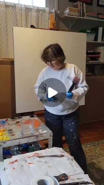 a woman standing in front of a painting easel with paint and brushes on it