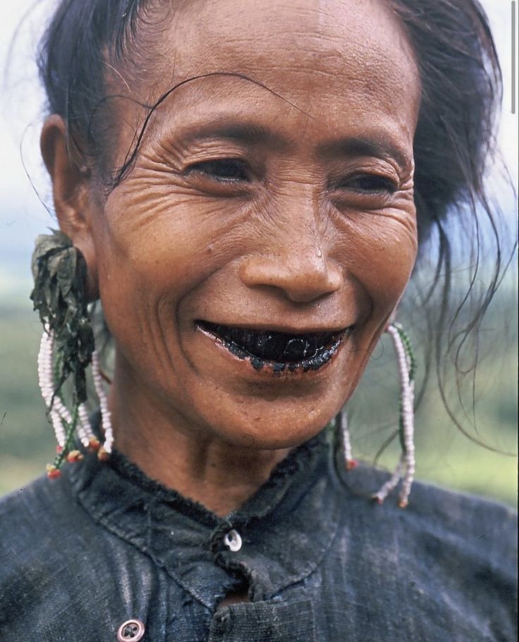 an old woman with fake teeth and piercings on her face smiles at the camera