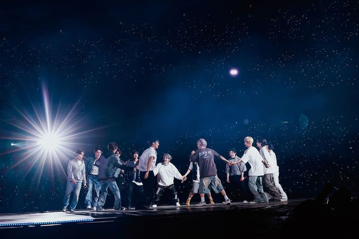 a group of young men standing on top of a stage with their arms around each other