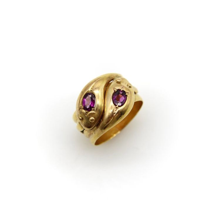 This is part of Chairish’s Fine Jewelry assortment.  This is a classic 9k gold snake ring that has two beautiful rhodolite garnets in the head of each snake. The snake heads interlock   and the garnets are bead set into a mount that are carved to look like tulips. The oval rhodolite garnets are a deep purple pink and have a beautiful fire to their rich, reddish purple hue. The snakes have a cute mouth detail—almost like a smile—and their tails appear on each side of the ring. The wide ring band Pomegranate Ring, Tudor Jewelry, Historical Rings, Snake Heads, Persian Jewelry, Reddish Purple, Serpent Ring, Ring Pop, Rhaenyra Targaryen