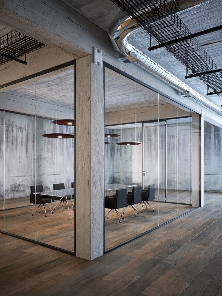 an empty office with glass walls and chairs in the middle is seen from across the room