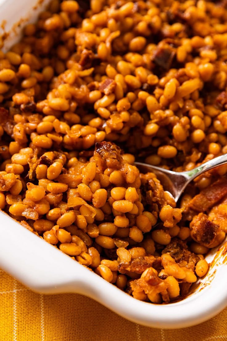 baked beans in a white casserole dish with a spoon